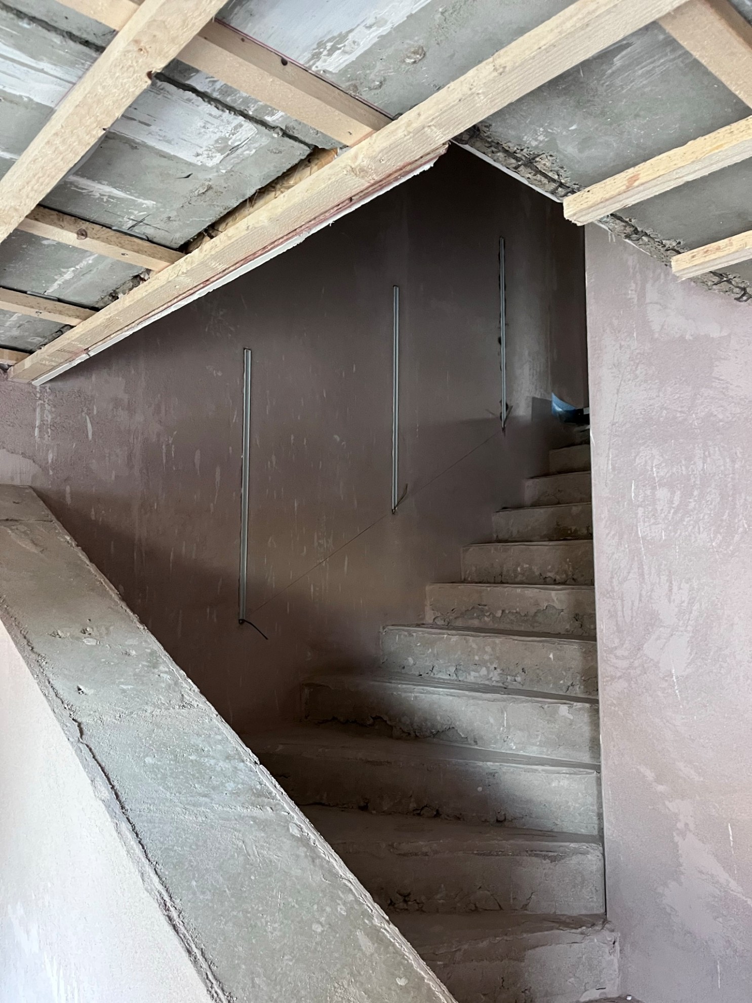 Rohbau-Treppenflur mit vorbereiteten Wandnuten für lineare LED-Beleuchtung entlang der Treppe