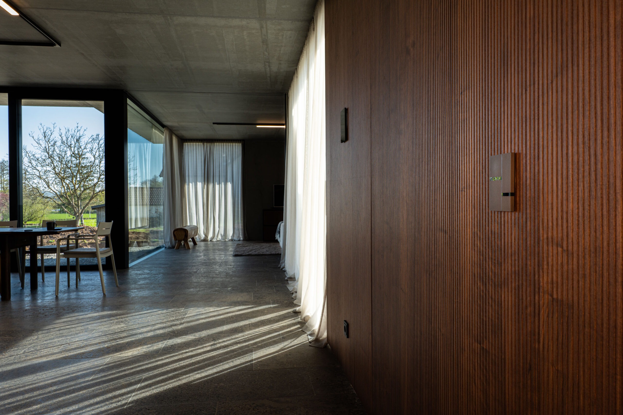 Basalte Fibonacci und Touch-Panel an hochwertiger Holzwand in offenem Wohnkonzept – FWZ Elektrotechnik Referenz Villa am Main.