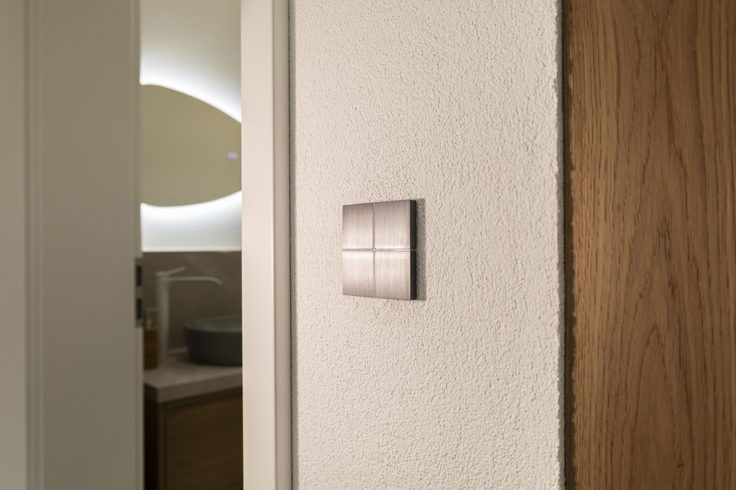 Basalte Sentido KNX-Taster aus gebürstetem Metall an weißer Putzwand – FWZ Elektrotechnik Smart Home Referenz.