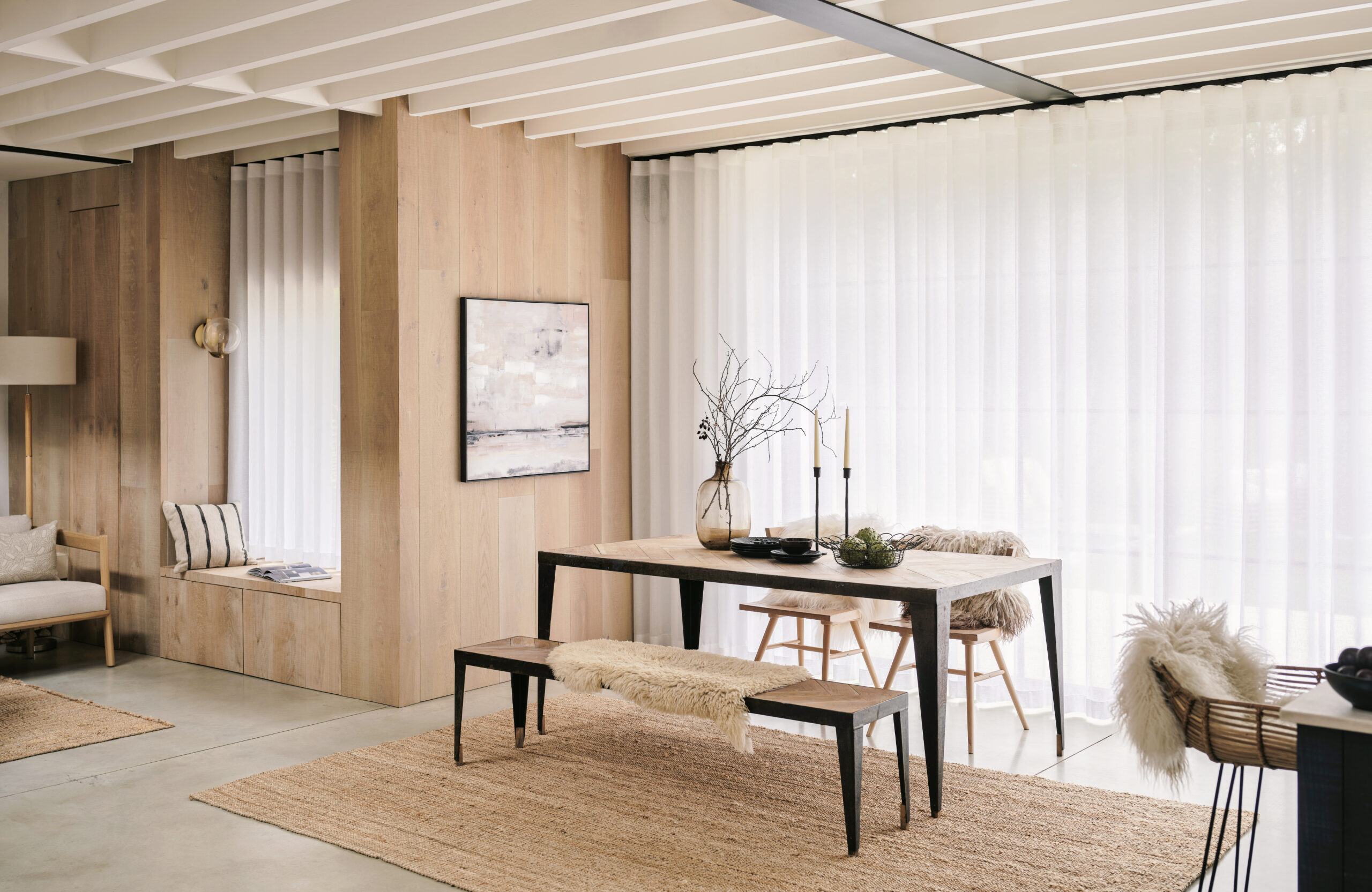 Wohnbereich mit deckenhohen Vorhängen, heller Holzgestaltung und hochwertiger, dezent integrierter Fensterbeschattung.