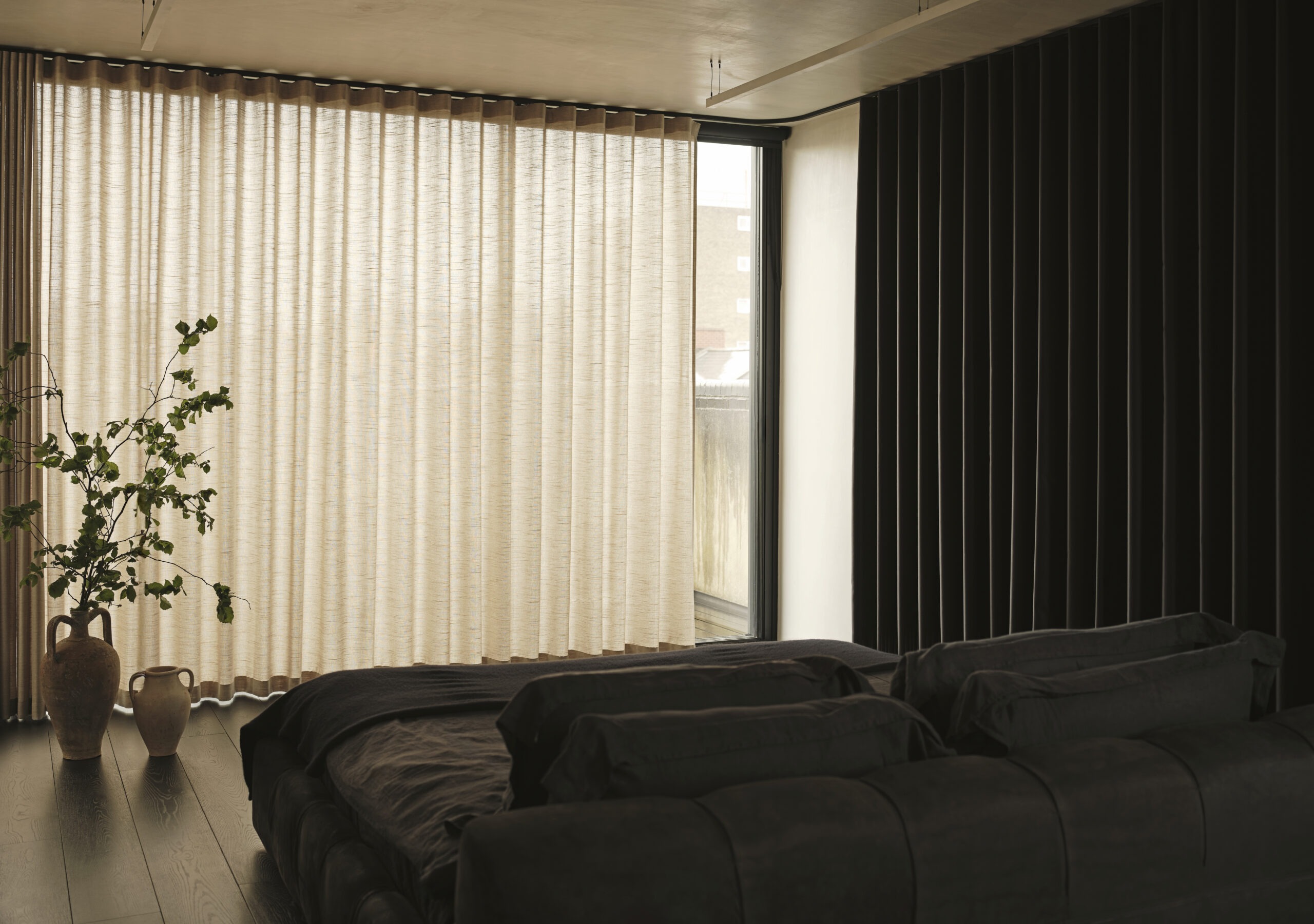 Wohnraum mit deckenhohen Vorhängen, großer Fensterfront und hochwertiger textiler Beschattung.