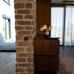 Moderner Wohnbereich mit Taster in der Natursteinwand, integrierten Steckdosen im Holz und hochwertiger Elektroinstallation.