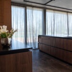 Schwarze Steckdosenleiste bündig integriert in Holzpaneel einer Luxusküche – FWZ Elektrotechnik Detail Villa am Main.