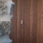 Basalte Fibonacci Luxus-Bedienteil auf Holzpaneel – Exklusive Smart Home Installation von FWZ Elektrotechnik in einer Villa am Main.