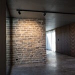 Moderner Innenraum mit Natursteinwand, dunkler Holzverkleidung und minimalistischer Lichtgestaltung.