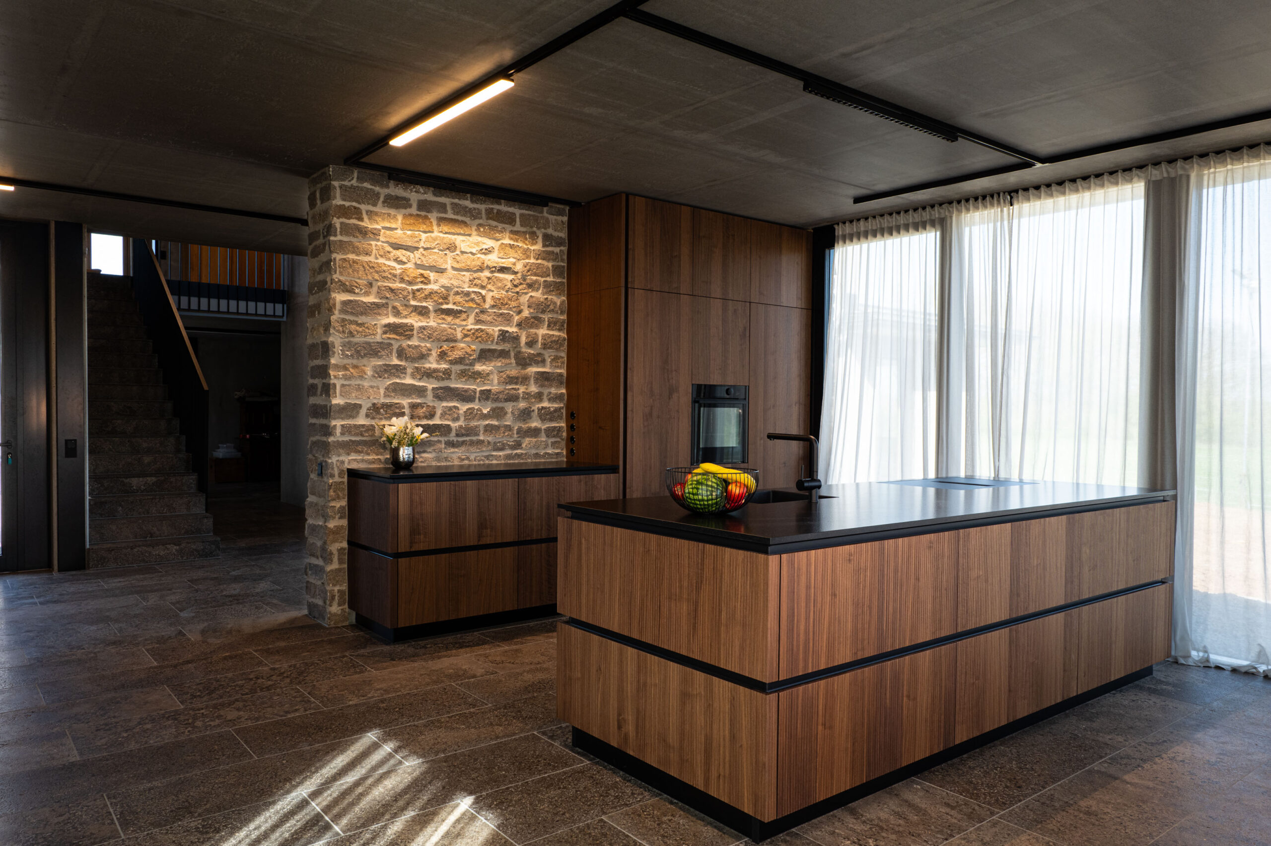 Exklusive Küchenbeleuchtung mit modernem Schienensystem und Akzentlicht an der Steinwand – FWZ Elektrotechnik Referenz Villa am Main.