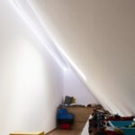 Lineare Beleuchtung in einer Spielhöhle unter der Dachschräge mit blenfreiem Licht entlang der Wand.