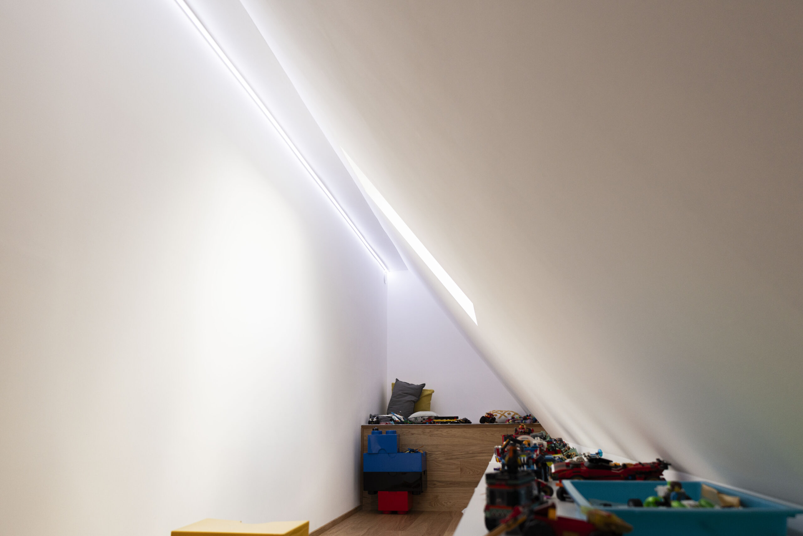 Lineare Beleuchtung in einer Spielhöhle unter der Dachschräge mit blenfreiem Licht entlang der Wand.