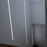 Treppenhaus mit vertikalen LED-Lichtlinien als moderne Orientierung- und Akzentbeleuchtung.