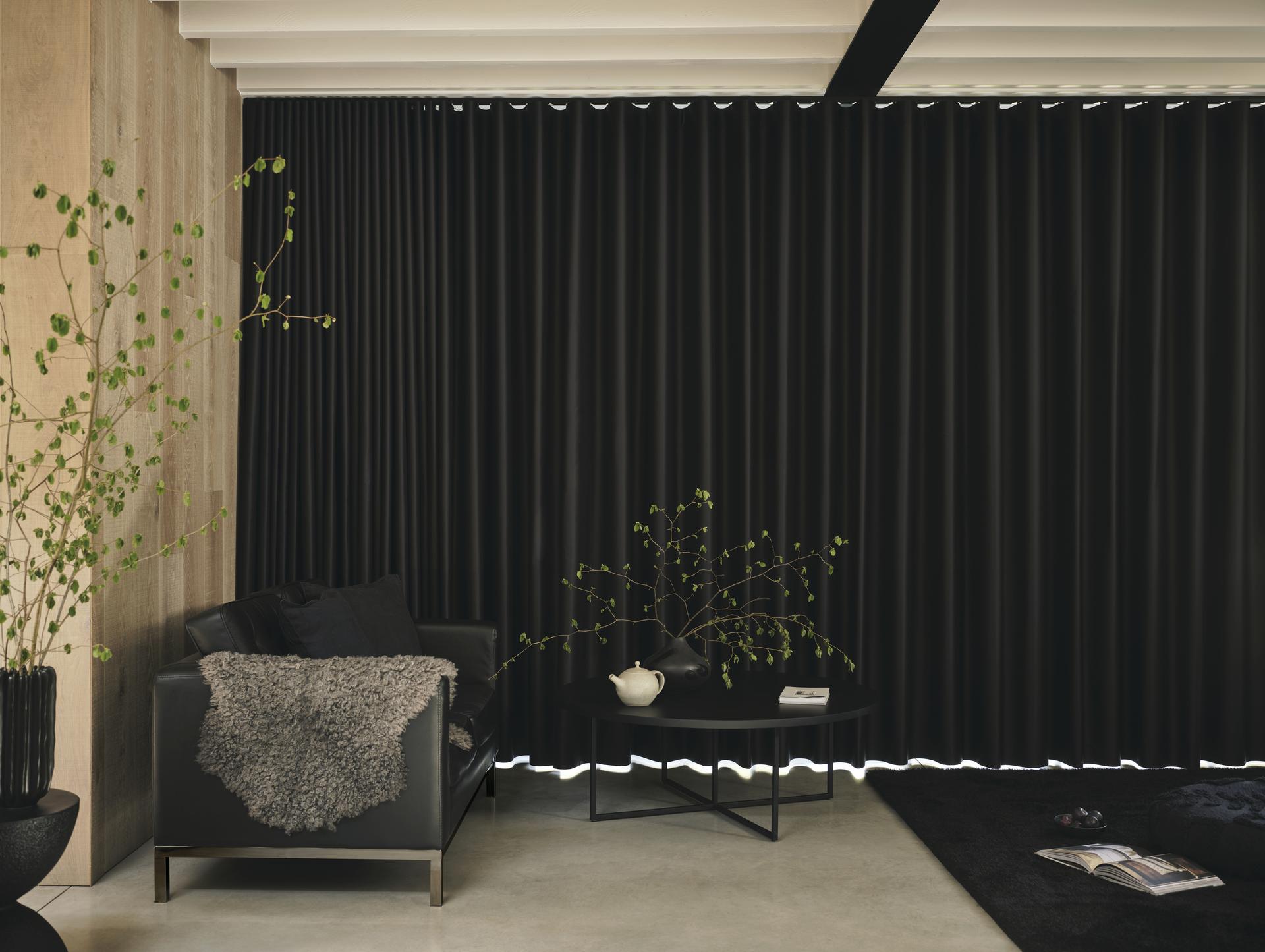 Wohnraum mit schwarzen deckenhohen Vorhängen als elegante textile Beschattung und Verdunkelung.