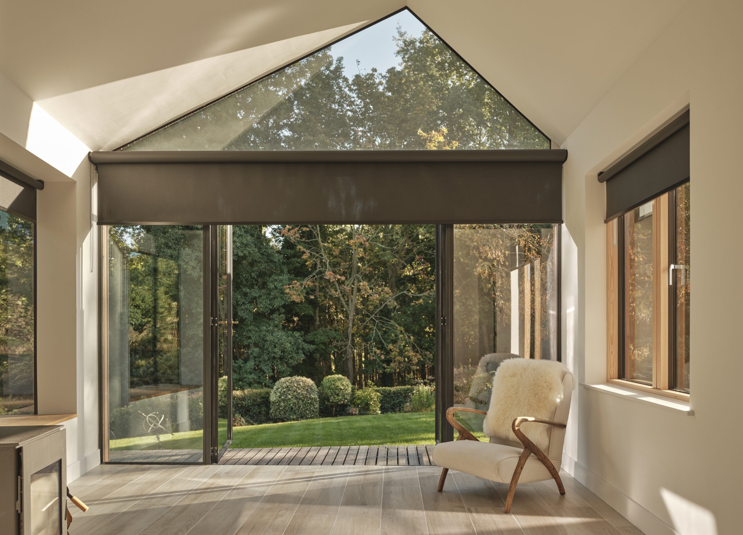 Wohnraum mit großflächiger Fensterfront, elektrischer Beschattung und dezent integrierten Rollos für Licht- und Sichtschutz.