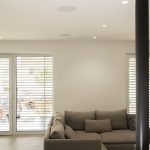 Deckenlautsprecher eines unsichtbaren Surround-Soundsystems im modernen Wohnzimmer mit Ecksofa