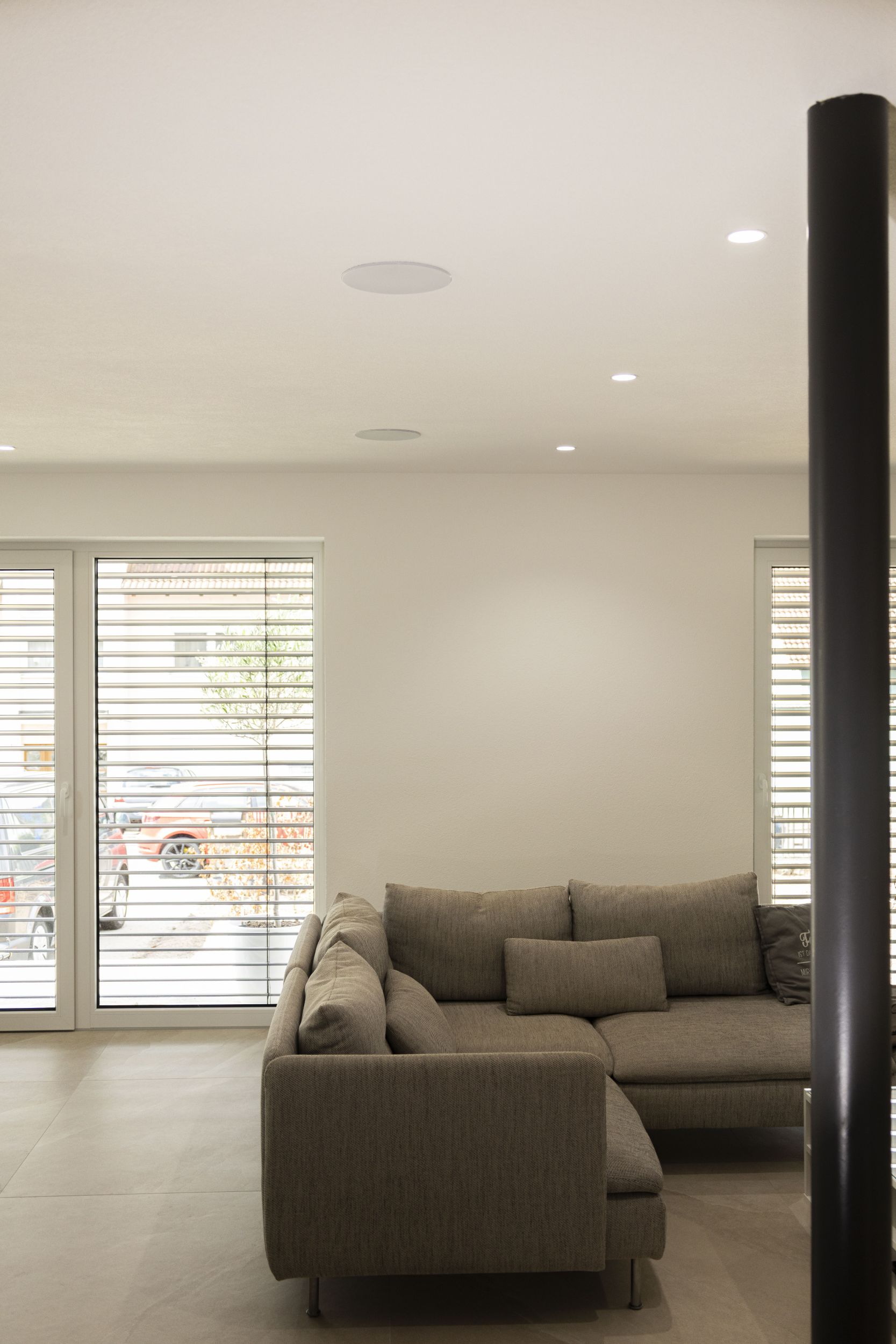 Deckenlautsprecher eines unsichtbaren Surround-Soundsystems im modernen Wohnzimmer mit Ecksofa